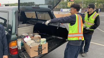 Two staff pulling large tv out of trunk