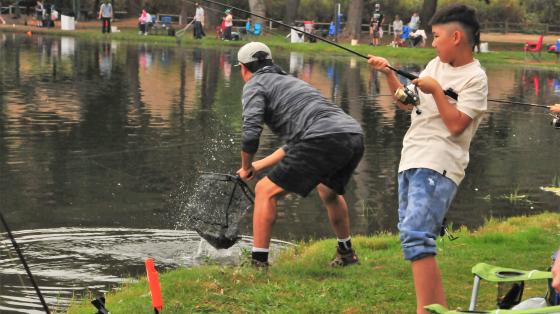 one kid and one adult fishing in lake