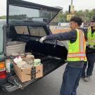 Two staff pulling tv out of trunk