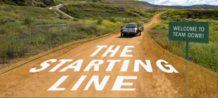 The Starting Line - long dirt road ahead with a white truck and people on it.
