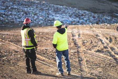 two workers looking at trash