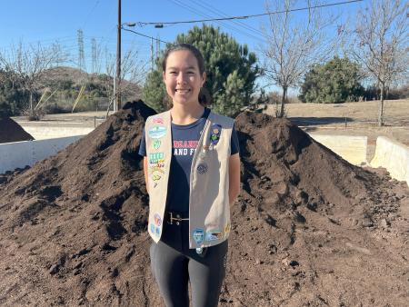 Photo of Bella in front of compost pile